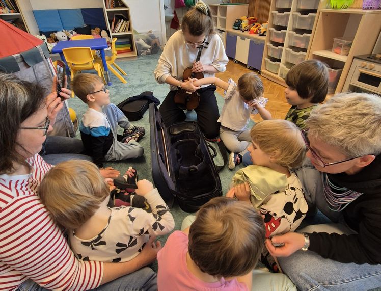 Dzieci z przedszkola podczas spotkania ze skrzypaczką - dzieci siedzą i słuchają