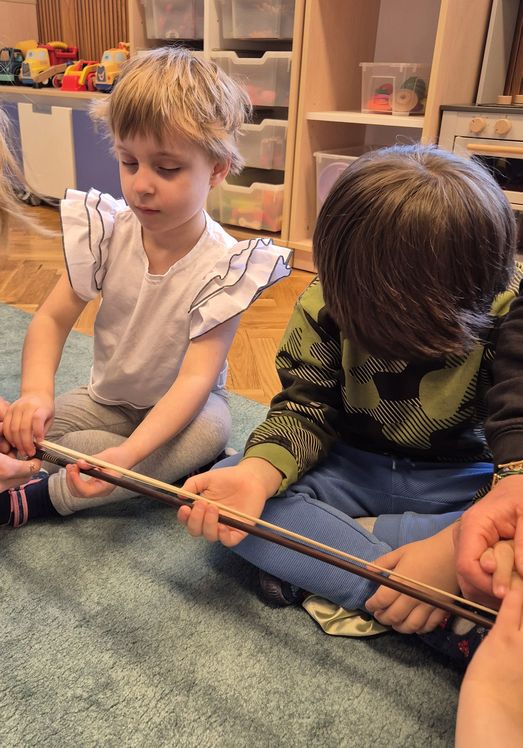 Zainteresowane dzieci słuchają wyjaśnień podczas spotkania ze skrzypaczką