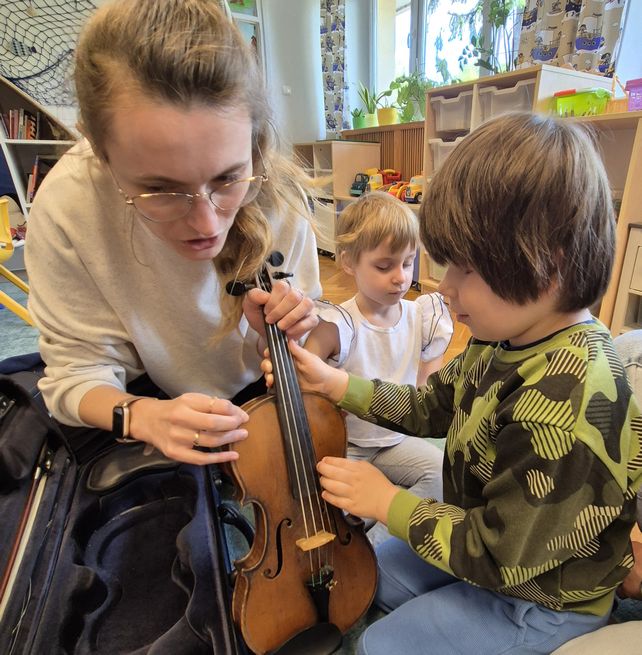 Skrzypaczka prezentuje budowę skrzypiec dzieciom - pokazuje elementy instrumentu